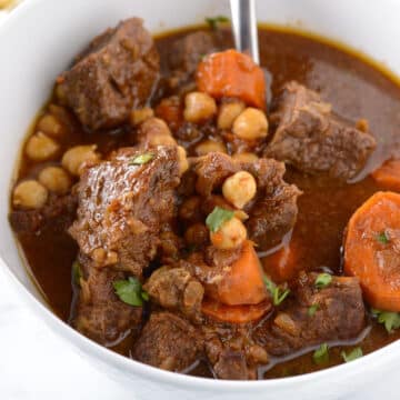 A top view of a white bowl with beef stew.