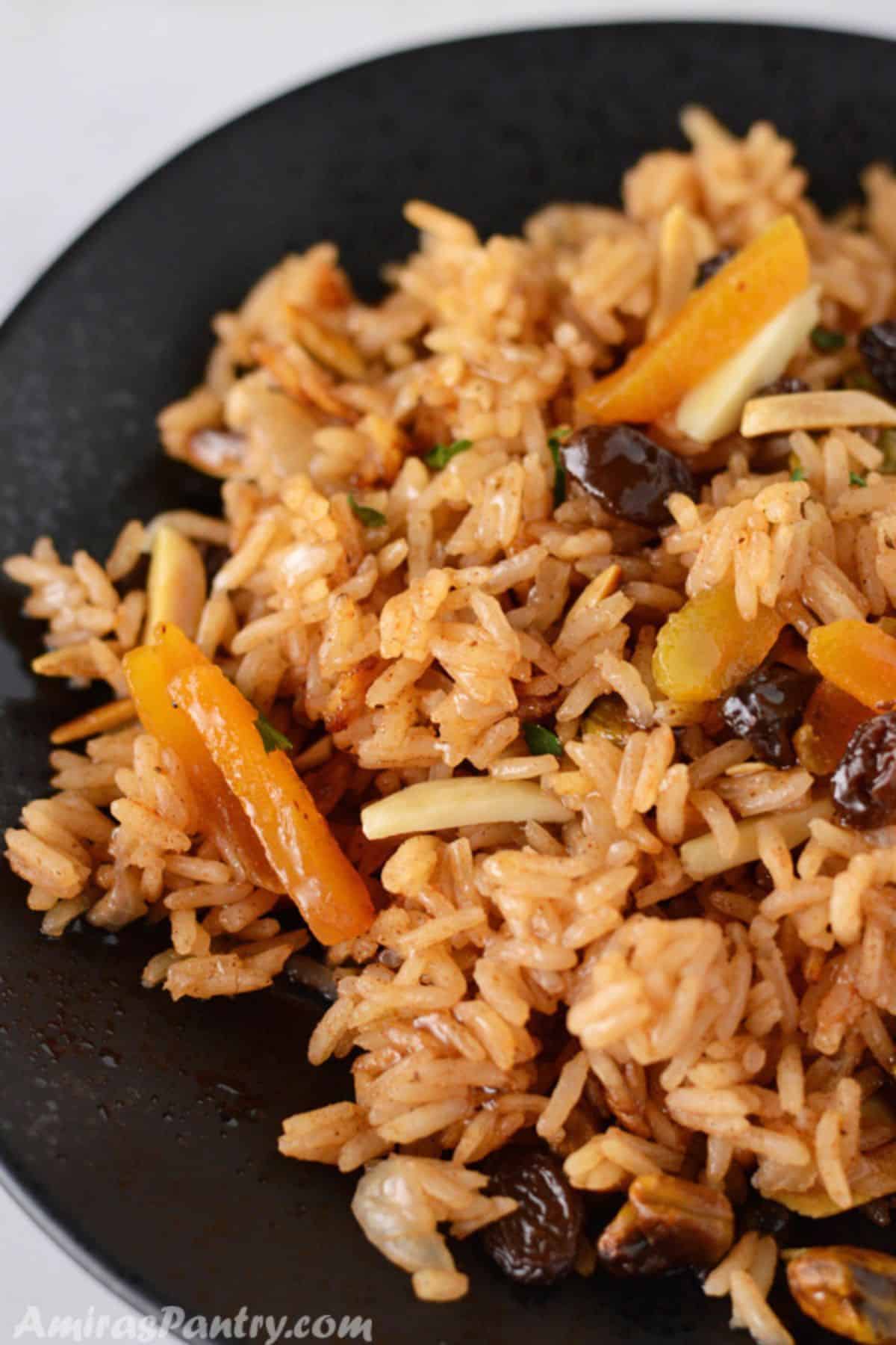 Mediterranean rice pilaf on a black dish garnished with dried fruits.