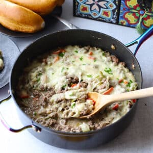 Philly cheesesteak casserole with a wooden spoon.