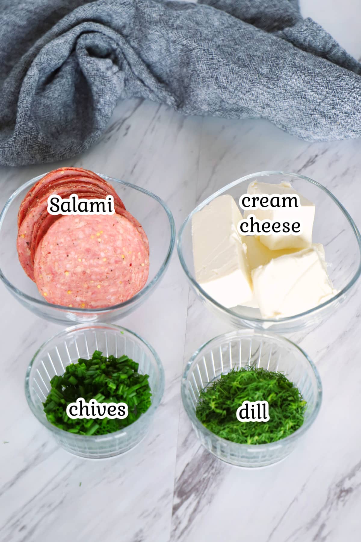 Salami roll ups ingredients on a marble surface.