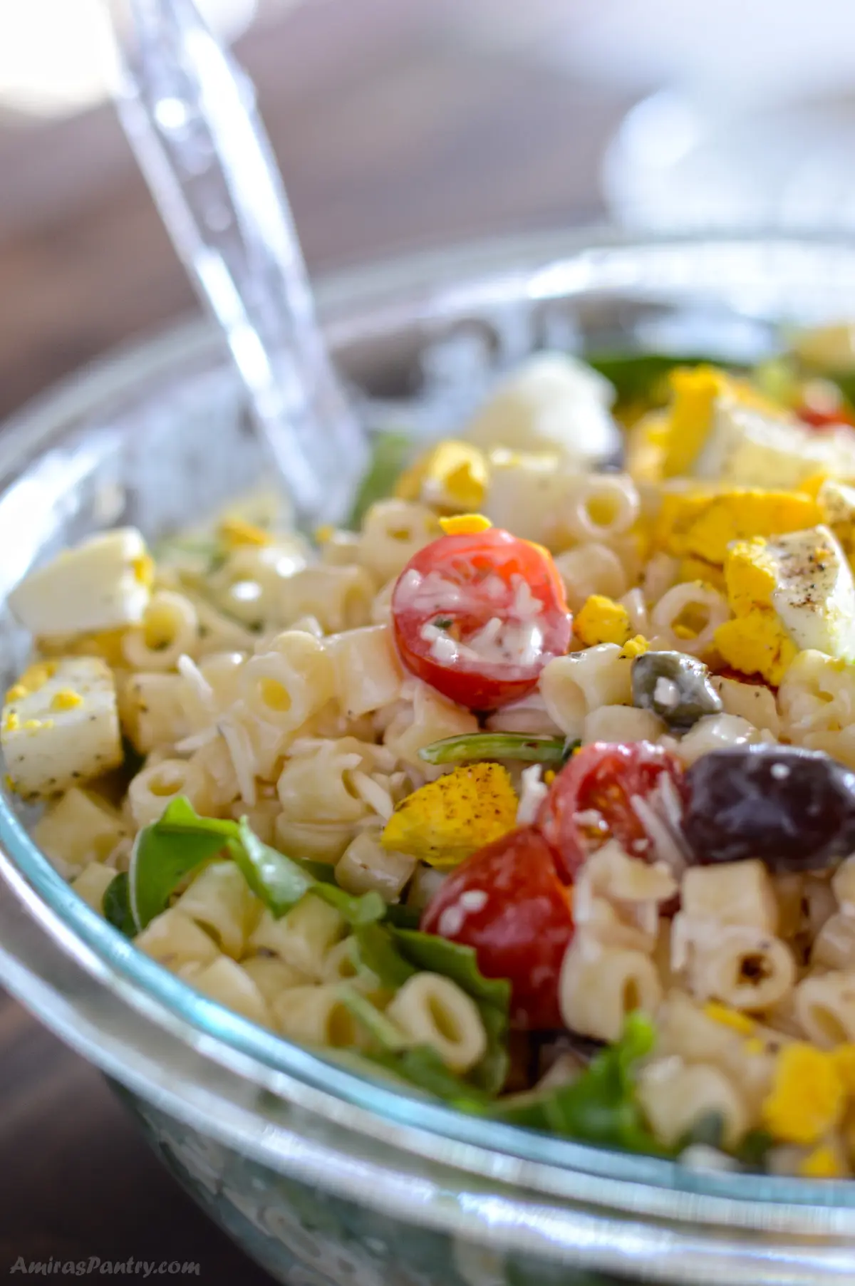 Ditalini pasta salad in a gladd bowl with a spoon in it.