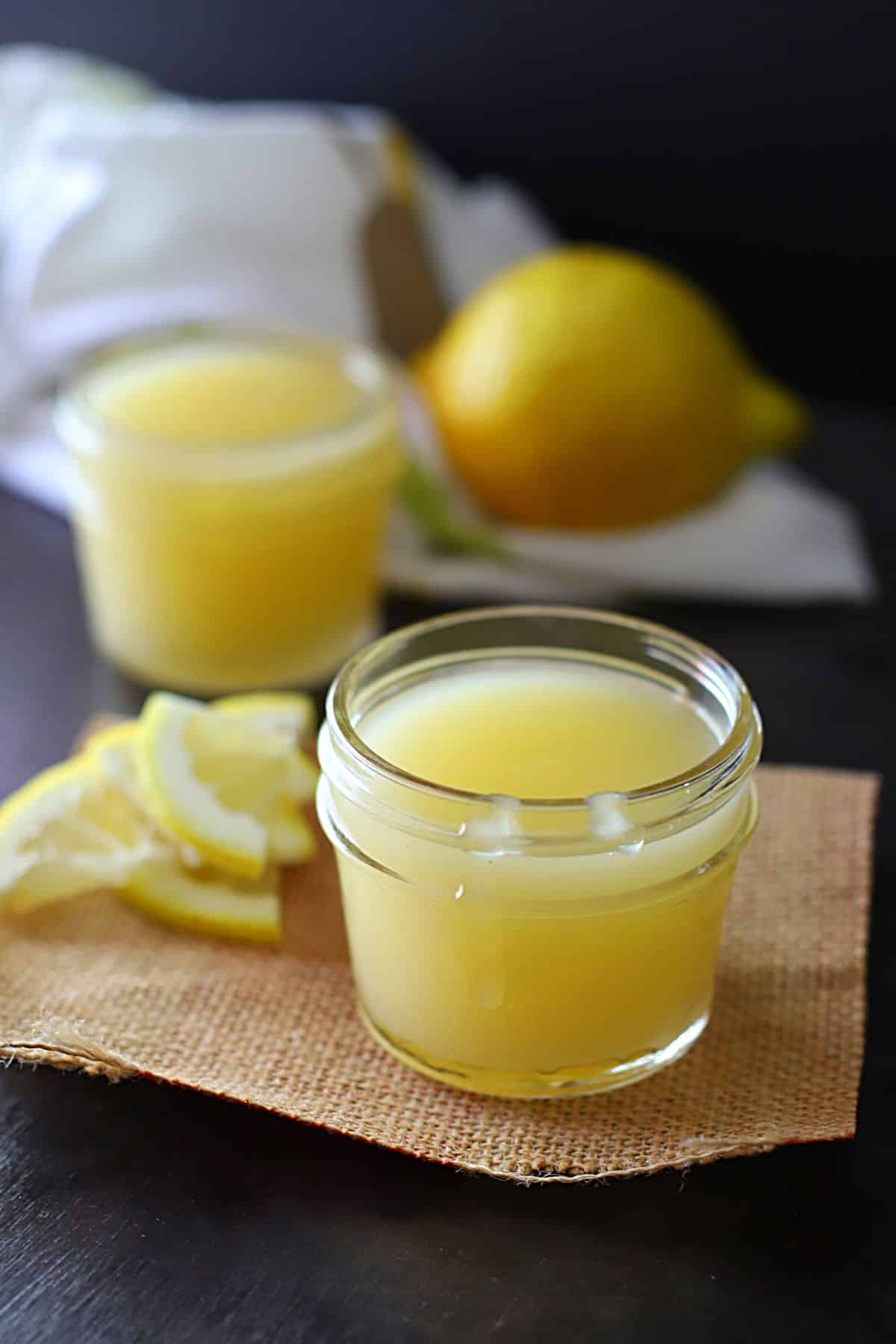 Small jars of easy lemon curds on a dark surface.