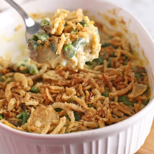 A spoon scooping some creamy green beans off a casserole.