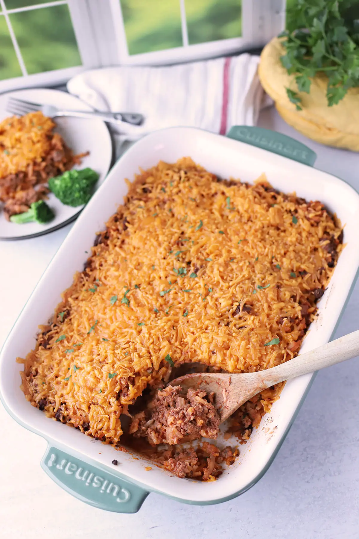 A bird's eye look at a ground beef hashbrown casserole with a wooden spoon.