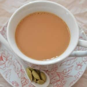 A top view of a cup with karak tea with some spices on the side.