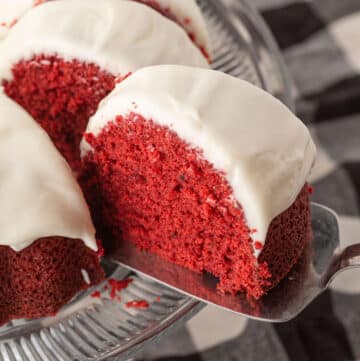 A cake serve pulling a slice of red velvet bundt cake.