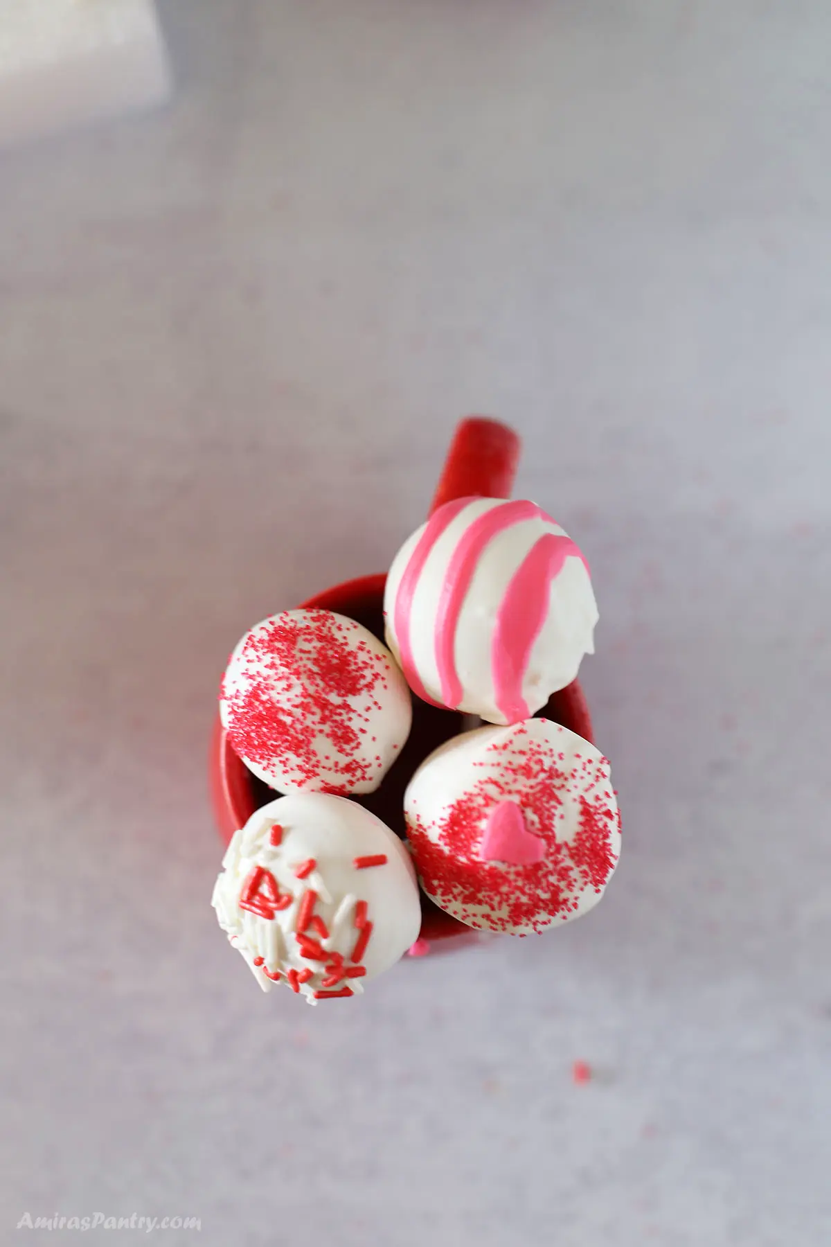 A top view of 4 strawberry cake pops on a red cup.