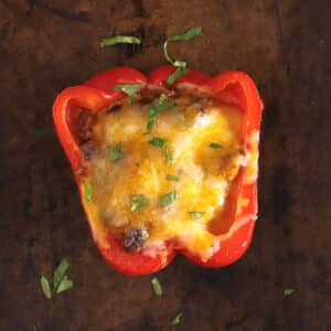 Stuffed bell pepper on a baking sheet topped with melted cheese.