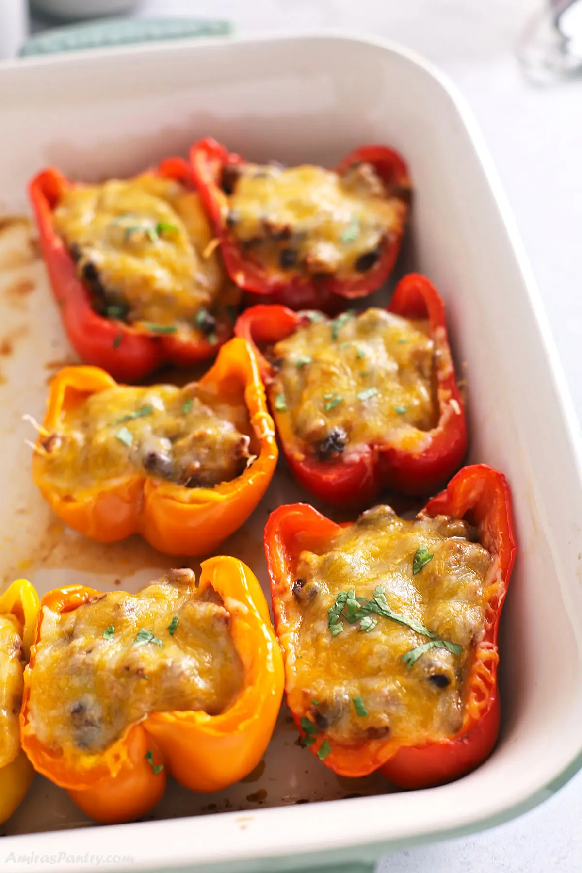A white casserole dish with taco stuffed bell peppers.
