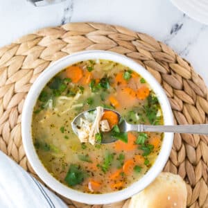 An overhead view of a white bowl with chicken and rice soup.