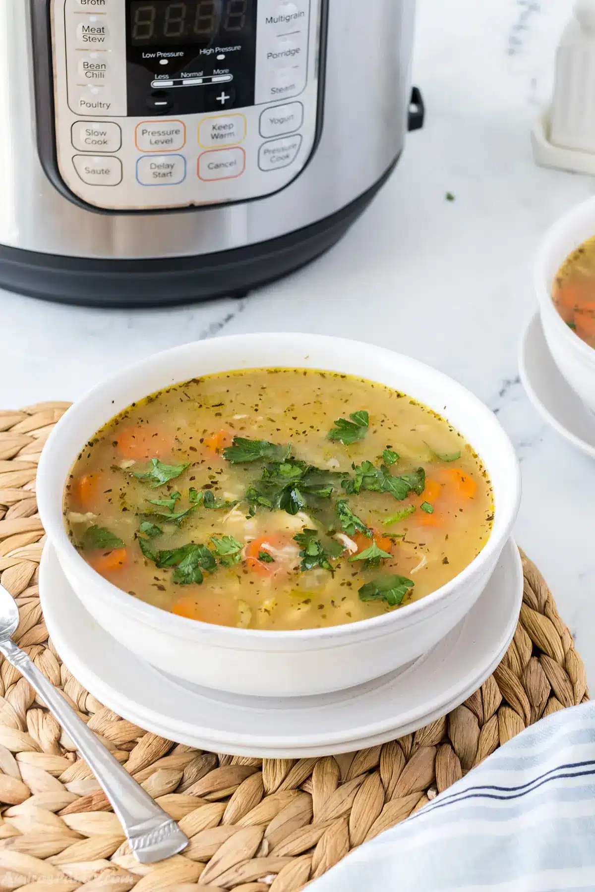 Chicken soup in a soup bowl with an instant pot in the back.