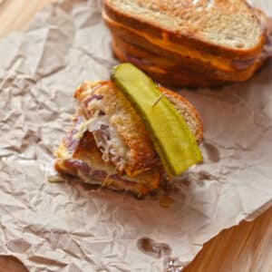 An overhead view of a half of a reuben sandwich with other sandwiches on the back.