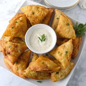 An overhead shot of sambusas on a white platter.