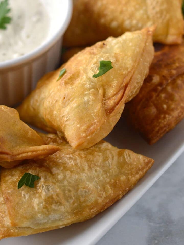 A pile od sambosa on a white platter.