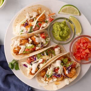An overhead view of a white plate with 4 baja shrimp tacos.