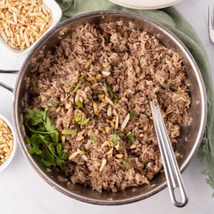 A large skillet of ground beef and rice with a spoon.