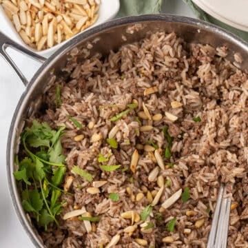 Overhead view of a skillet with ground beef and rice garnished with almonds.