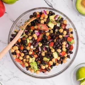 Av overhead view of a glass bowl with black bean and chickpea salad.