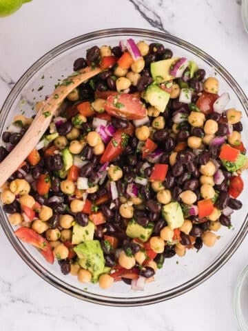 Av overhead view of a glass bowl with black bean and chickpea salad.