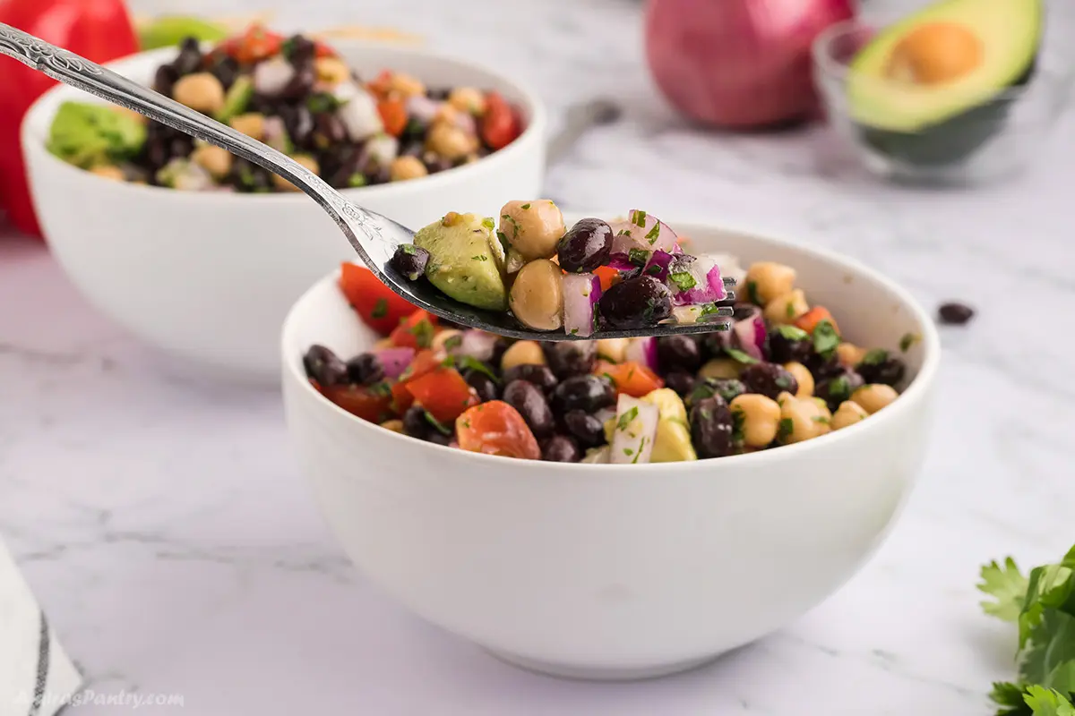 A forkful with black bean and chickpea salad on it.