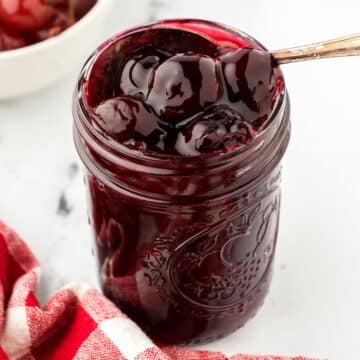 A close up look at a jar with cherry sauce.
