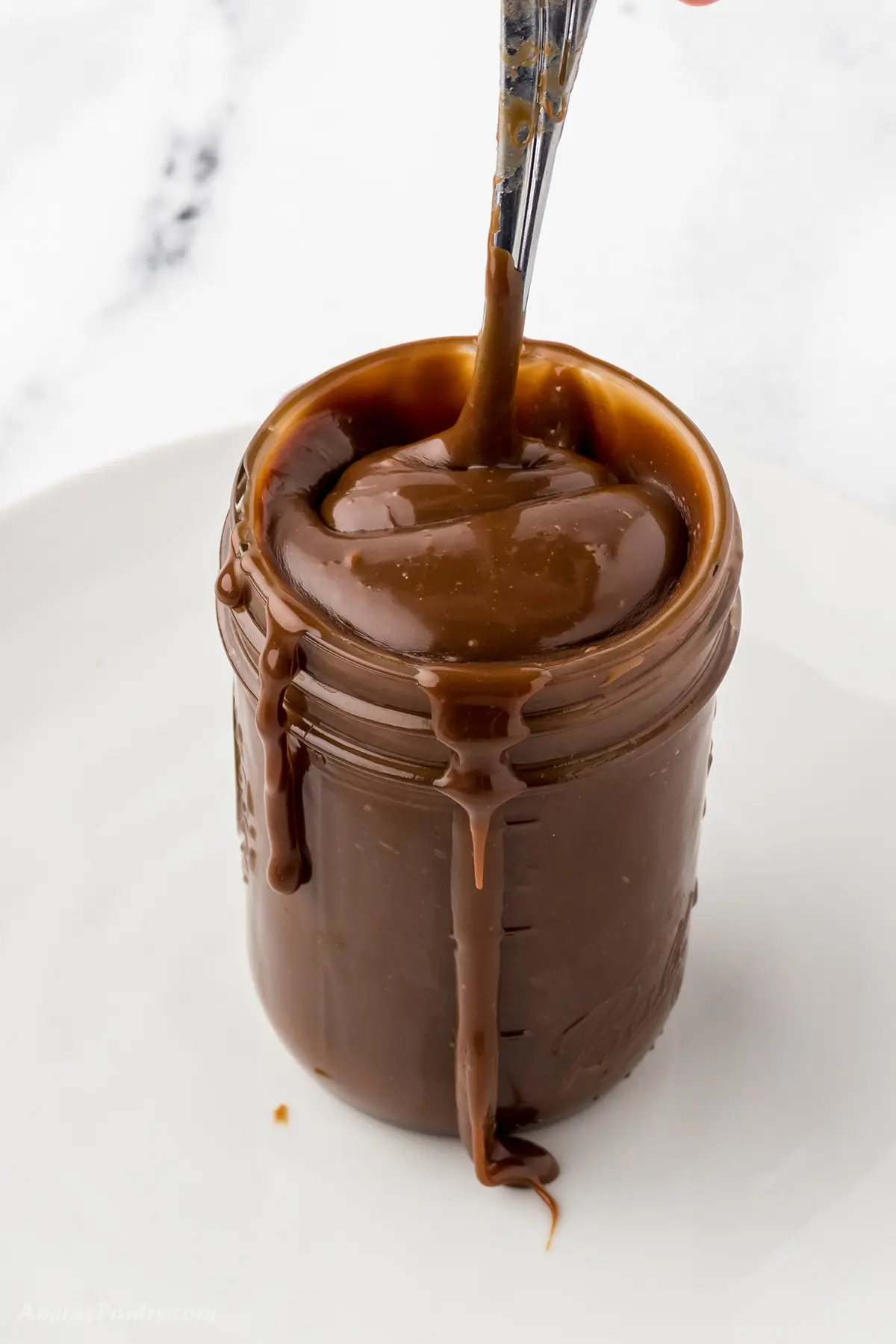 A jar of hot fudge sauce with a spoon.