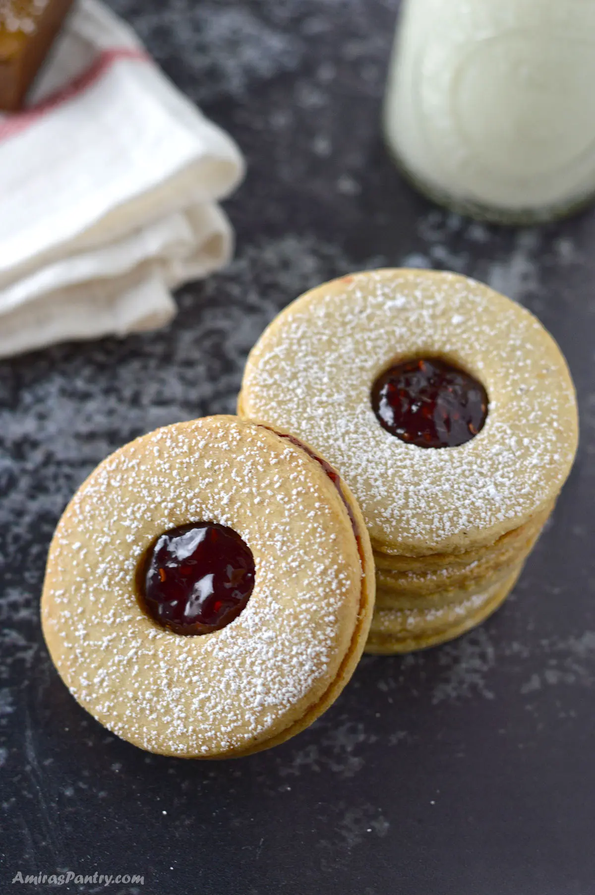 A stack of linzer cookies with a glass of milk.