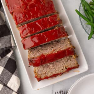 Meatloaf on a white plate cut into slices.