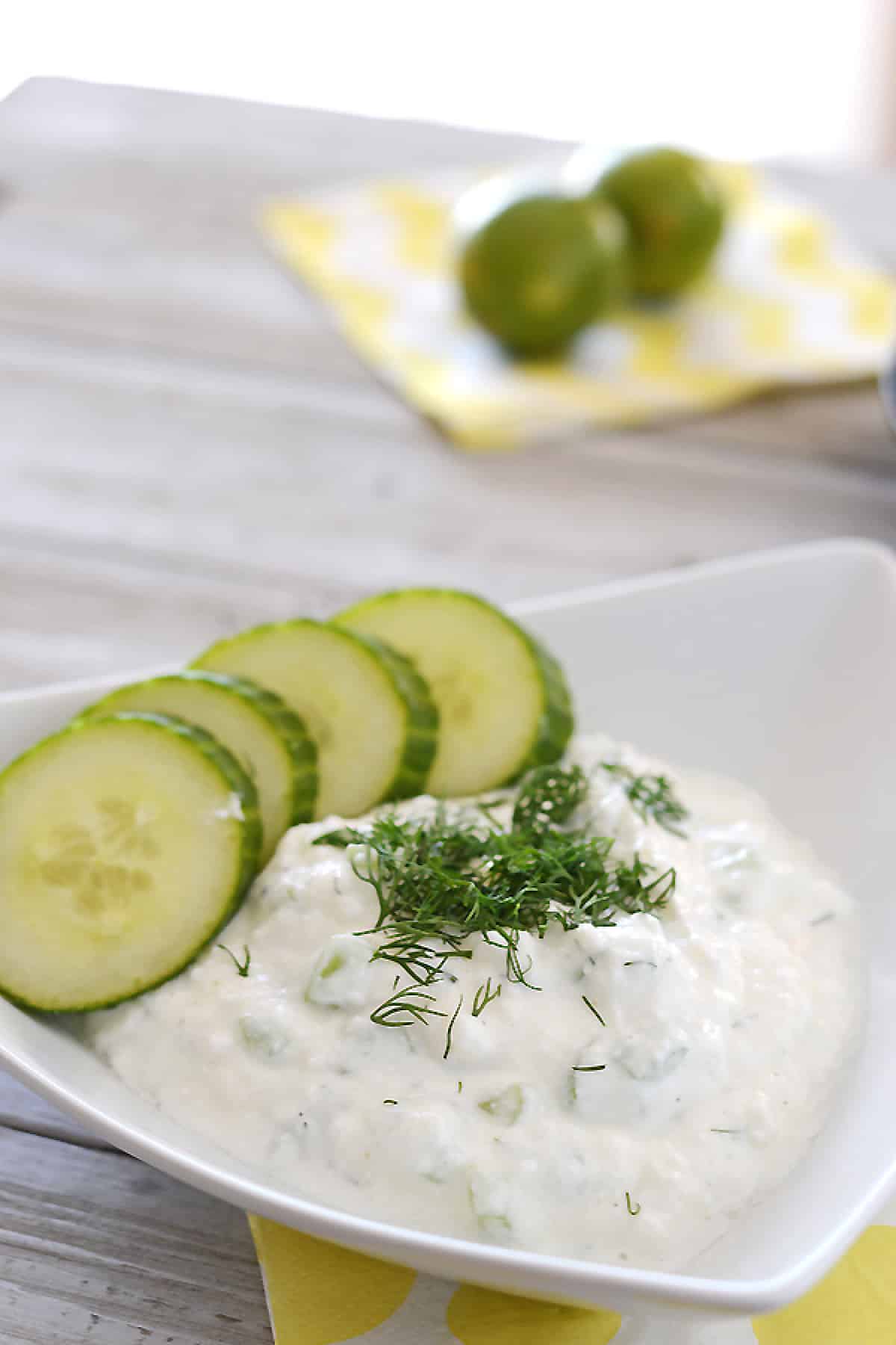 A white sering bowl with Greek yogurt sauce carnished with dill.