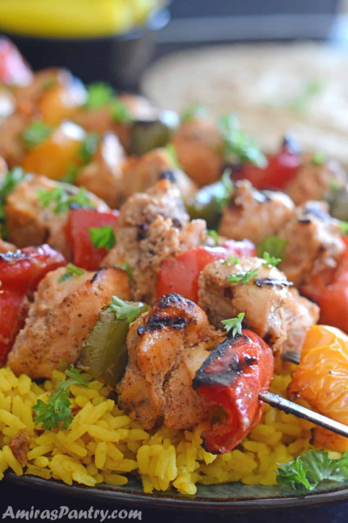 A close up of food, with Chicken kabob skewers on a plate.