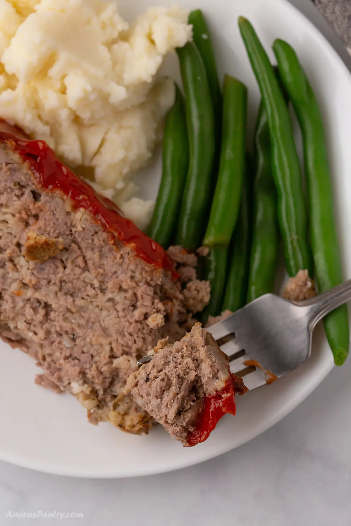 A plate wirh a slice of meatloaf with mashed potatoes.