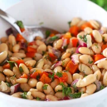 A zoom in image of a white bowl with bean salad.