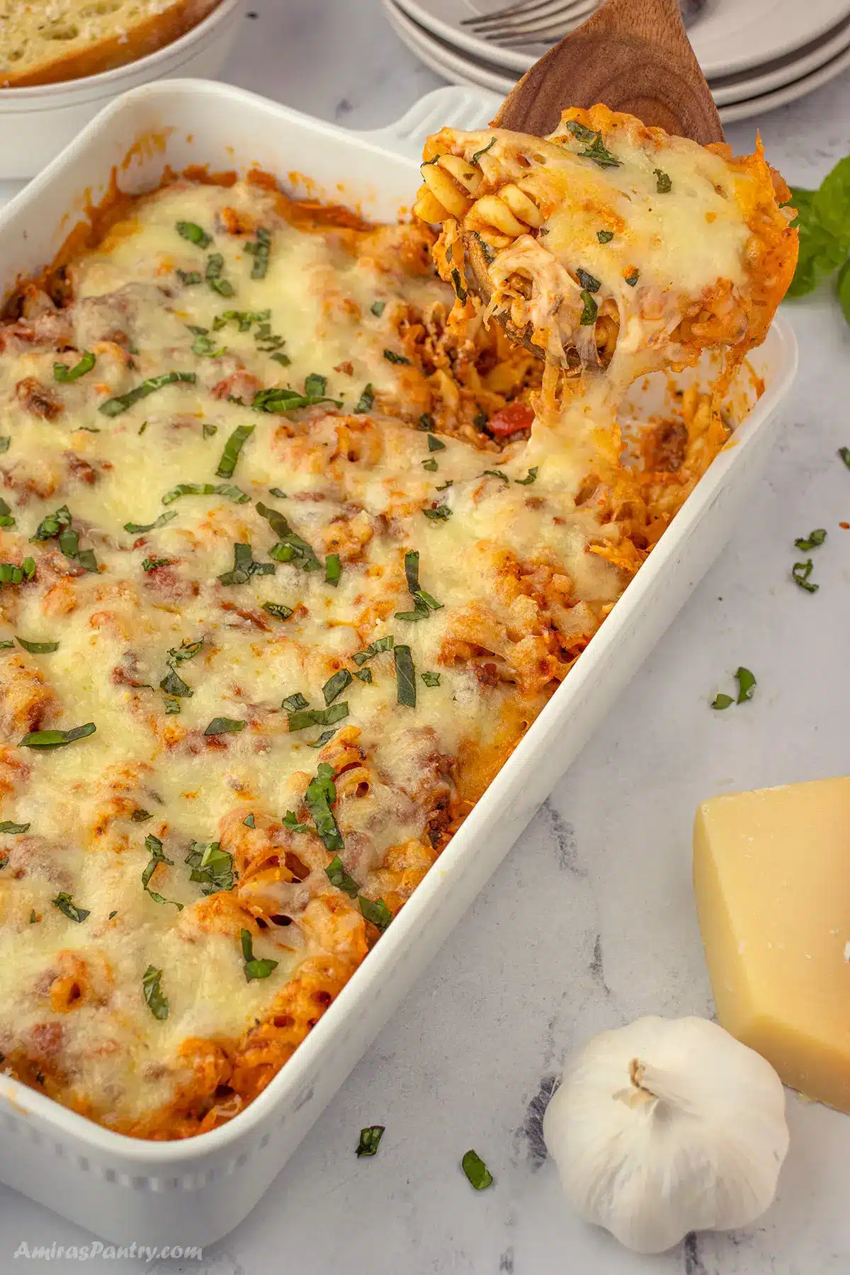 Easy lasagna casserole garnished with fresh herbs with a serving wooden spoon.