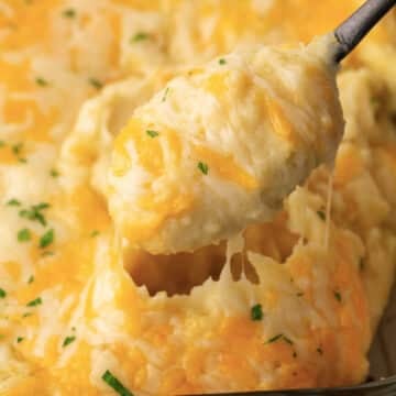 A spoon scooping some cheesy mashed potatoes.