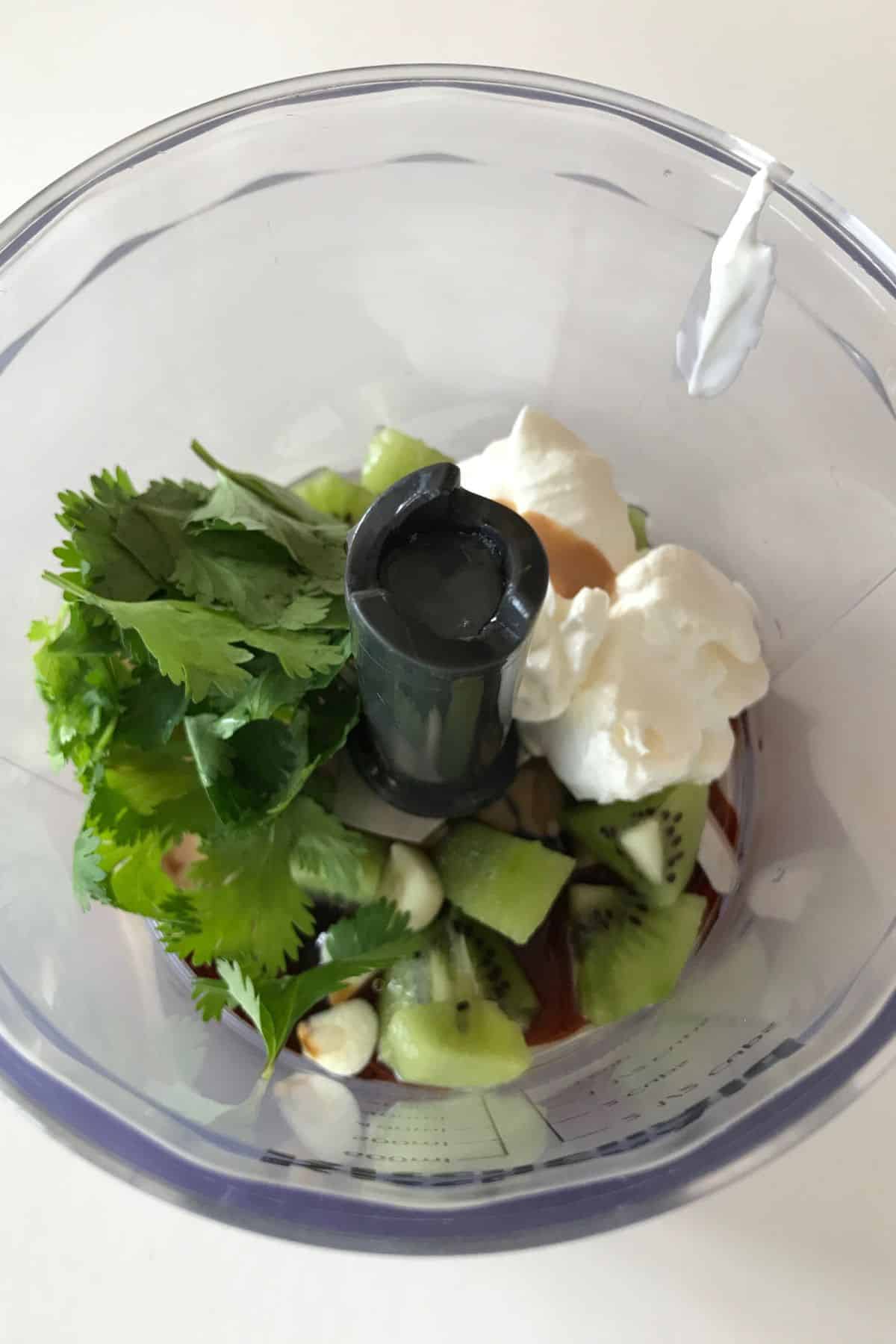 A food processor cup with dressing ingredients.