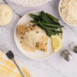 A white plate with a serving of creamy lemon chicken.
