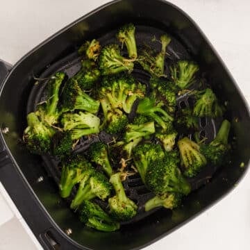 Top view of air fried frozen broccoli in air fryer basket.