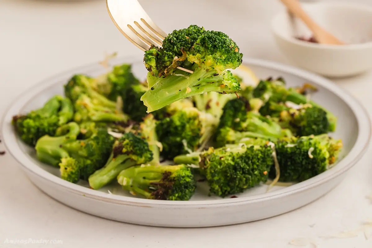 A fork with a piece of air fried broccoli.