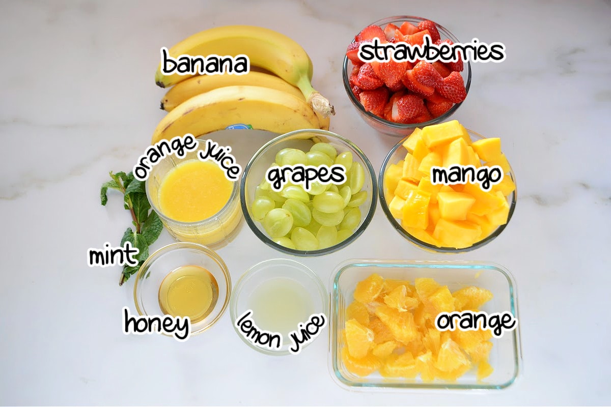 Fruit salad ingredients on a white surface.