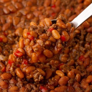 A close up image of a spoon with baked beans.