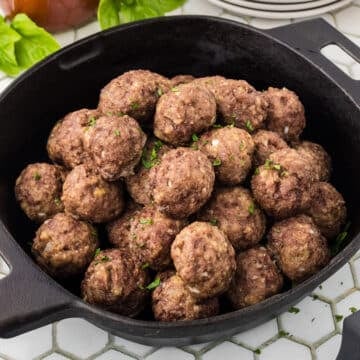 A side view of a cast iron skillet with bison meatballs.