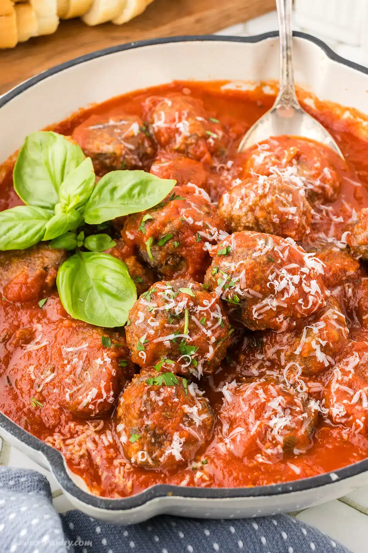 A white skillet with bison meatballs in tomato sauce.