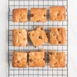 A top view of chocolate chip blondies squares on a wire rack.
