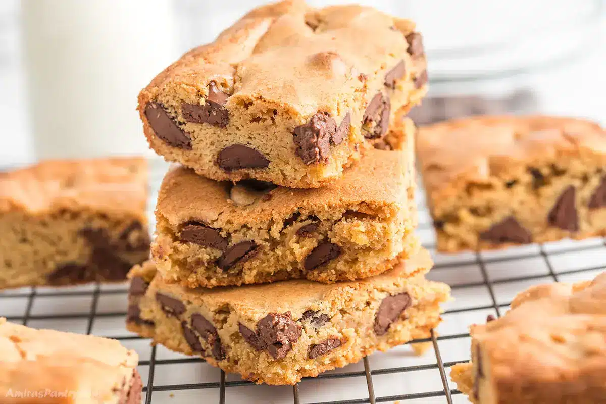 A stack on chocolate chip blondies on a cooling rack.