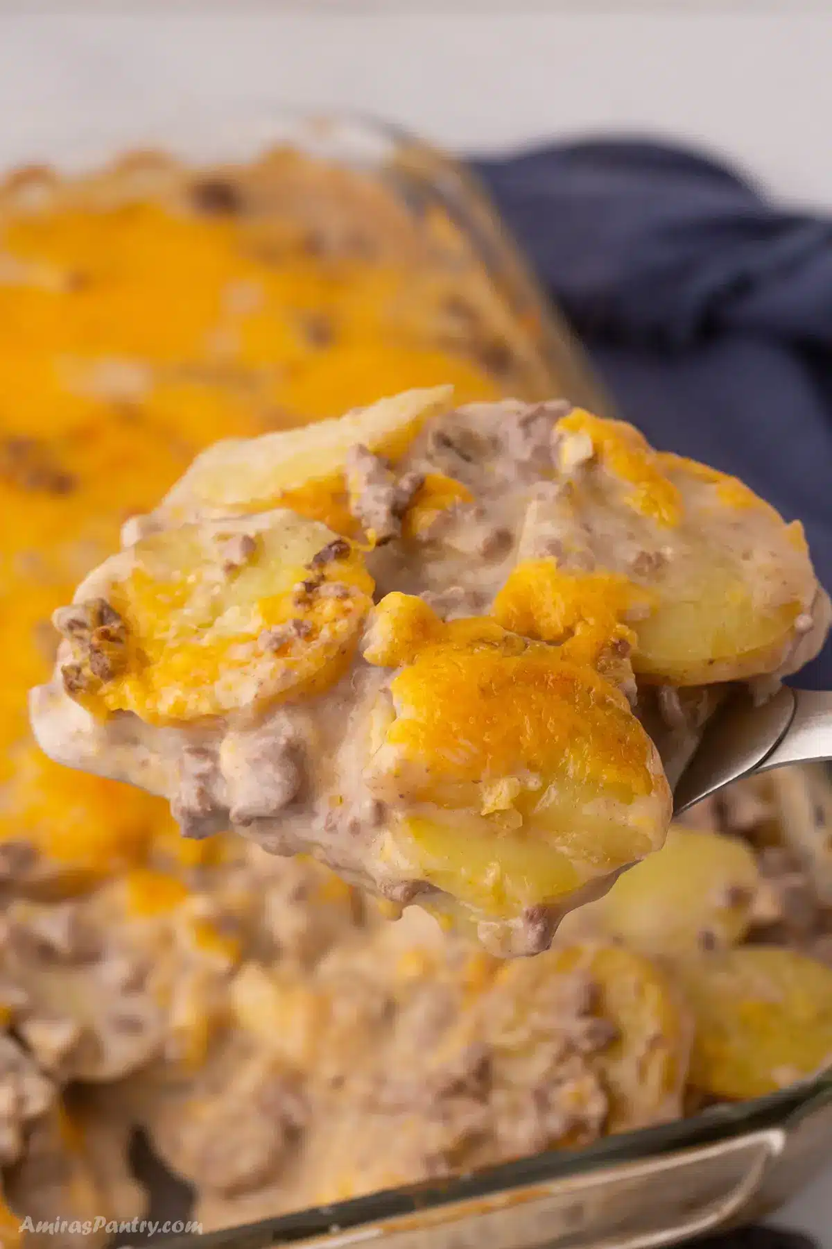 Hamburger potato casserole with a spoon taking a serving out of it.