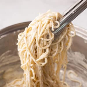 A close up look at kitchen tongue with some creamy pasta.