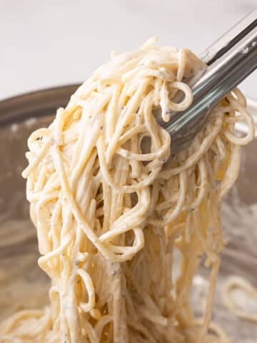 A close up look at kitchen tongue with some creamy pasta.