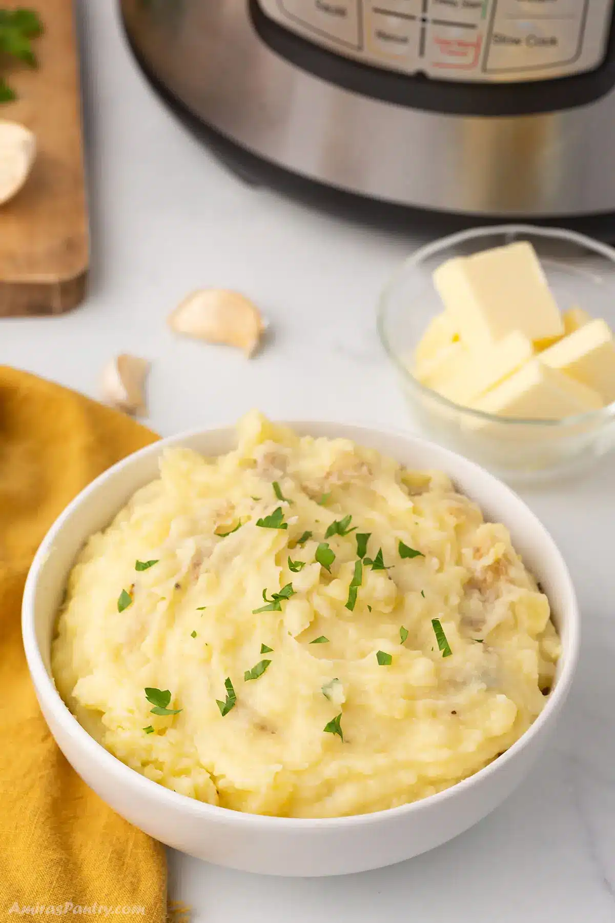 A big bowl of mashed potatoes with an instant pot in the back.