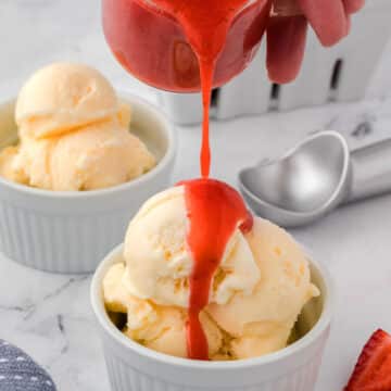 Strawberry coulis being poured on vanilla ice cream.