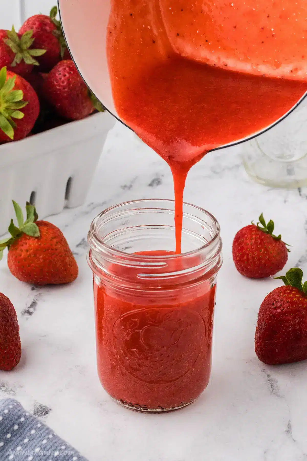 Strawberry sauce being poured into a jar.